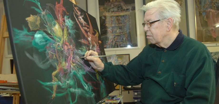 Ein Mann malt mit einem Pinsel an eine Leinwand