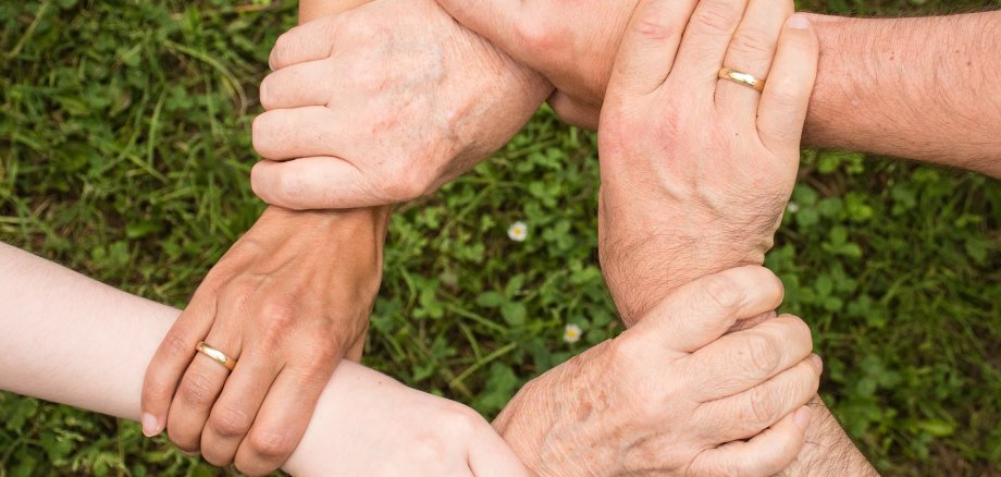 Hände symbolisieren Zusammenhalt und Gemeinschaft Vier Hände halten sich gegenseitig