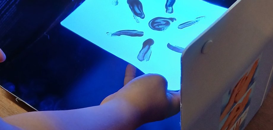 Mit Sonnencreme gemalte Sonne im UV-Licht
