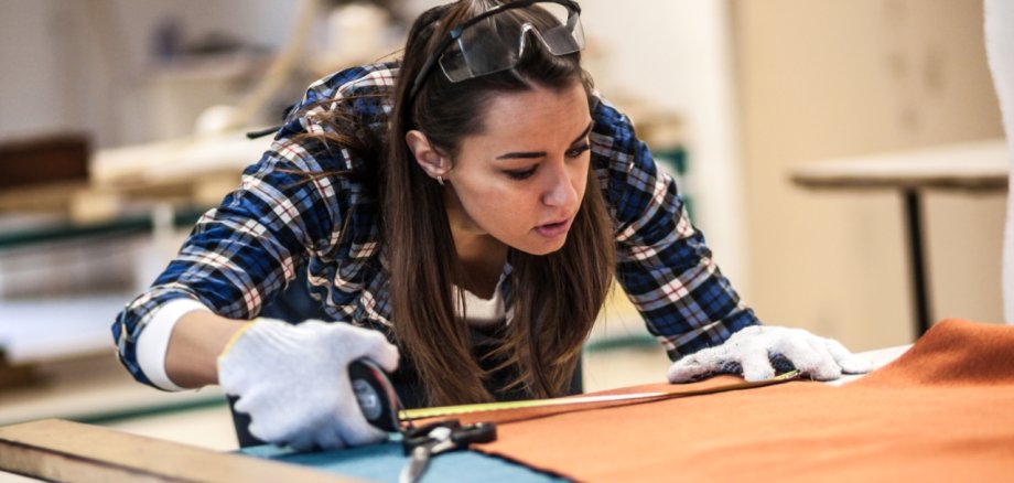 Young female fashion designer cutting fabric with scissors
