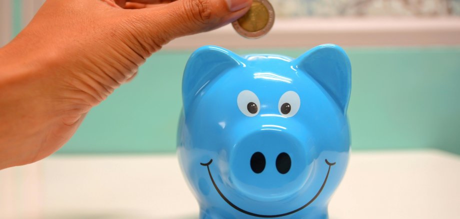 Geld wird ins Sparschwein gegeben