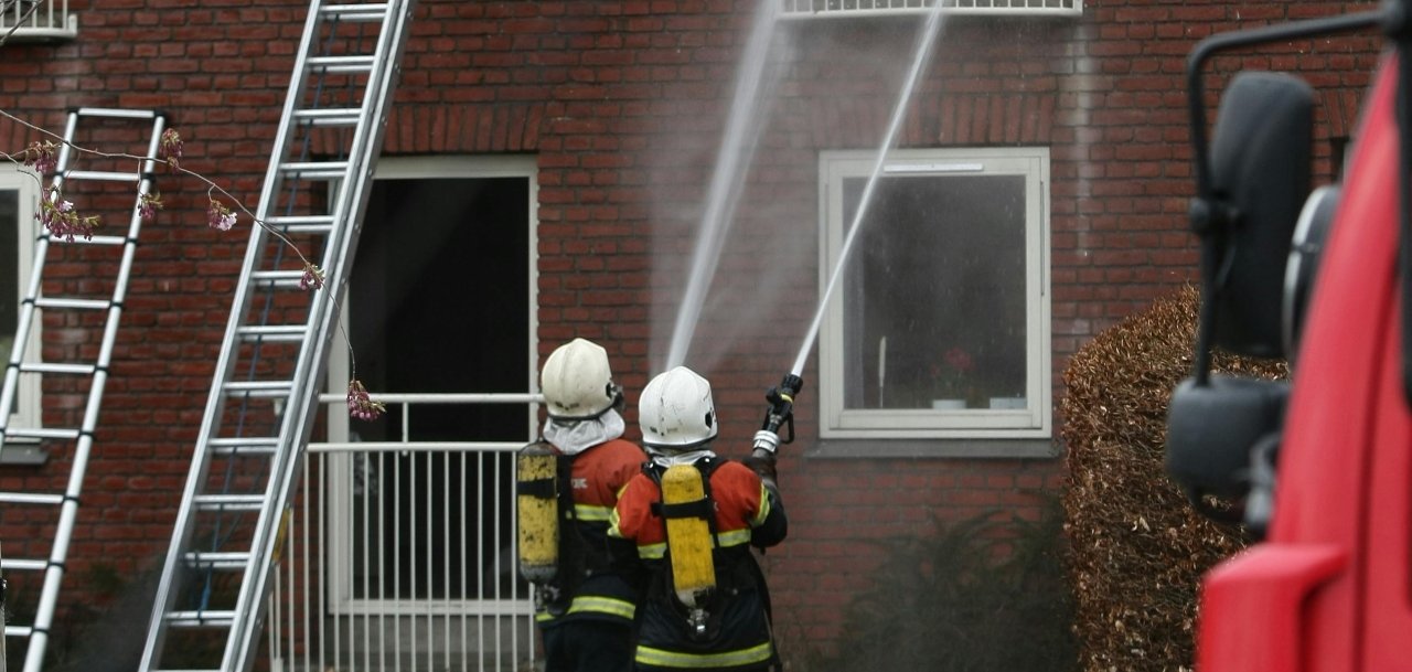 Feuerwehr bei Hausbrand Zwei Feuerwehrleute löschen einen Hausbrand