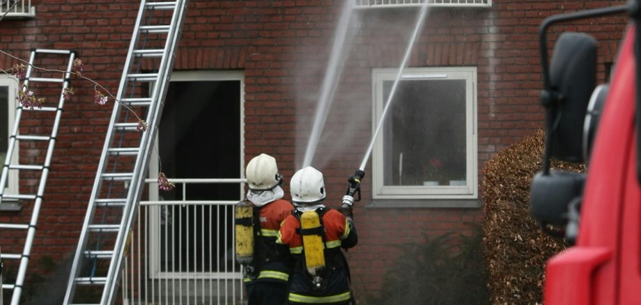 Zwei Feuerwehrleute löschen einen Hausbrand