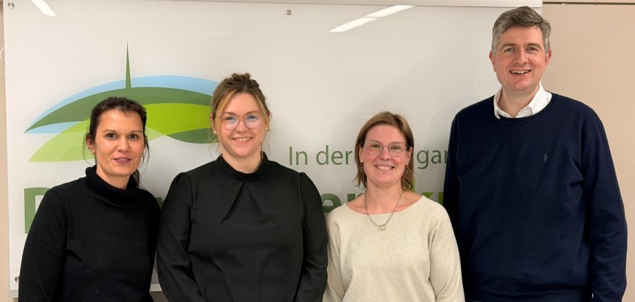 Vier Personen vor dem Logo des Donnersbergkreises