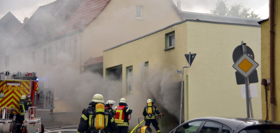 Ein brennendes Haus mit Feuerwehrleuten