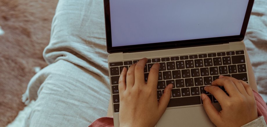 Blick auf einen Computer, der von einem Menschen auf dem Sofa genutzt wird