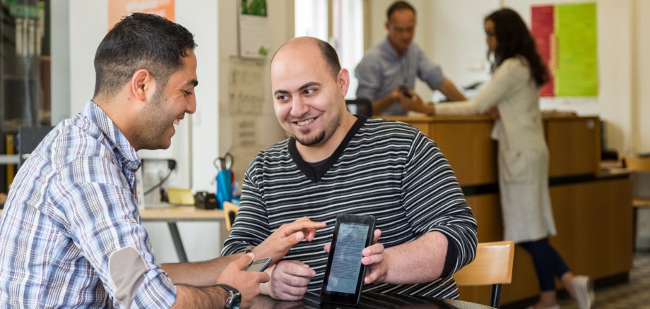 Zwei Männer an einem Tisch mit einem Tablet