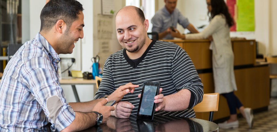 Zwei Männer an einem Tisch mit einem Tablet