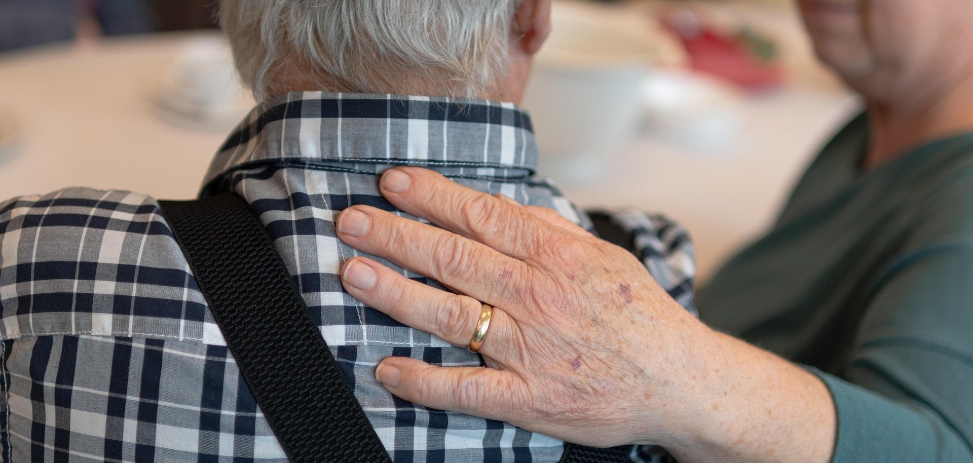 Eine Frau legt ihre Hand unterstützend auf den Rücken eines Mannes