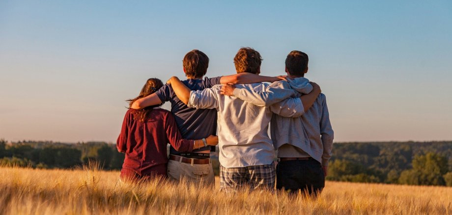 Vier Jugendliche von hinten in einem Feld