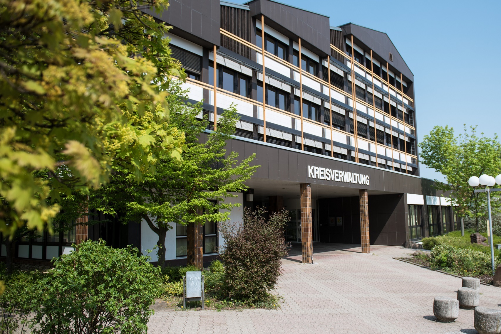 Kreishaus 2018 Im linken Vordergrund hängen belaubte Zweige ins Bild, das Kreishaus ist scharf im Hintergrund.