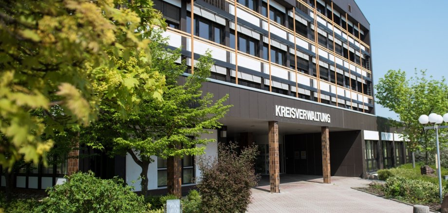 Im linken Vordergrund hängen belaubte Zweige ins Bild, das Kreishaus ist scharf im Hintergrund.