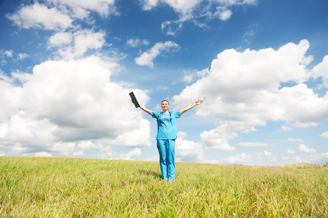 Eine junge Ärztin steht auf einer Wiese