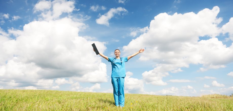 Eine junge Ärztin steht auf einer Wiese