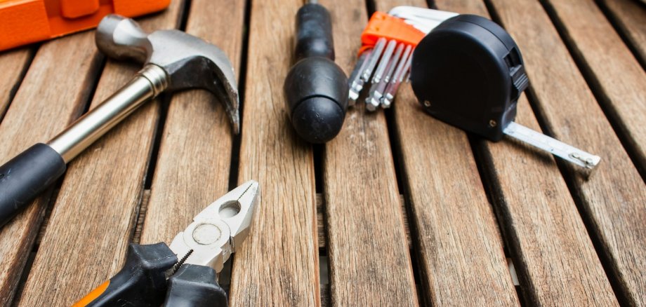 Hammer, Maßband und Zange auf Holztisch