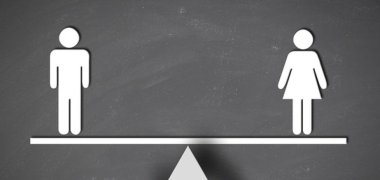 Symbolbild für Gleichstellung: eine Waage, auf der eine männliche und weibliche Figur an den Enden stehen 